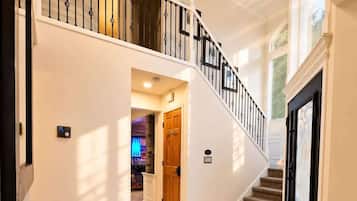 A spacious interior with a marble floor, a grand staircase, and a modern light fixture.