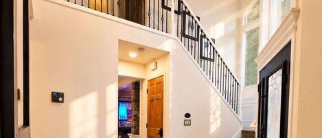 A spacious interior with a marble floor, a grand staircase, and a modern light fixture.