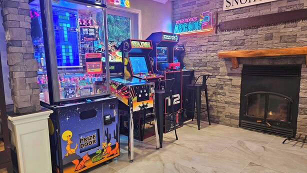 Un salón de juegos con varias máquinas recreativas, una chimenea y un letrero de neón que dice "SNOHOMISH".