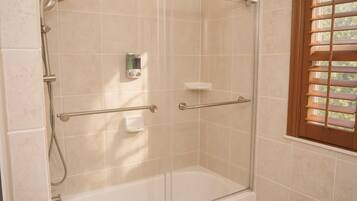 A glass-enclosed shower with a handheld showerhead, a handheld shower attachment, and a handheld shower attachment.