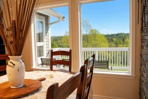 Un espace repas comprenant une table, des chaises et donnant sur un balcon agrémenté d’une balustrade.