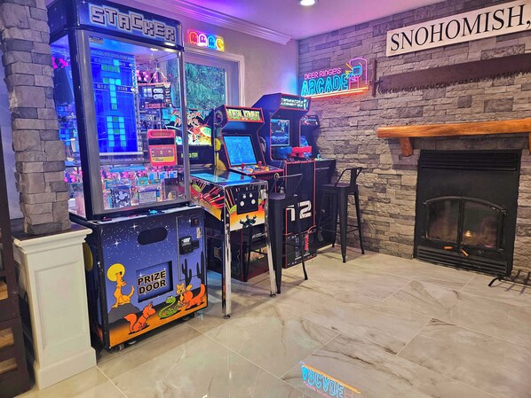 Une salle d’arcade proposant divers jeux, une cheminée et un panneau néon sur lequel on peut lire « SNOHOMISH ».