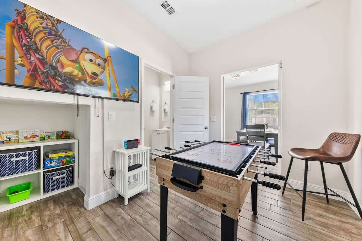 A room with a foosball table, a TV, and a bookshelf.