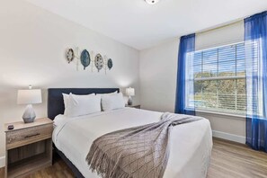 A bedroom with a bed, nightstands, a window with curtains, and wall art. - Pool * Game Room * Mins to Disney (Kissimmee)