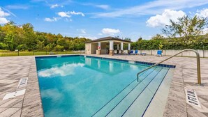 A swimming pool with a covered pavilion, lounge chairs, and a fence. - Pool * Game Room * Mins to Disney (Kissimmee)