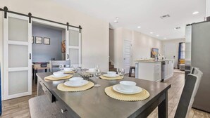 A modern kitchen with a dining area, a sliding door, and a refrigerator. - Pool * Game Room * Mins to Disney (Kissimmee)