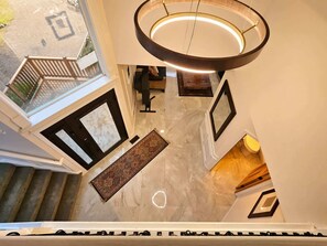 A high-ceilinged interior with a circular light fixture, a patterned rug, and a view of the outdoors through a window. - Private Bedroom w Hot Tub and Arcade (Snohomish)