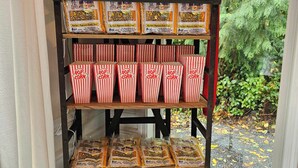A display of All-N-One Premium Tri-Pak popcorn in red and white striped boxes and bags.