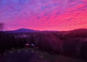 A landscape with a mountain in the background and a small building with a red roof near a body of water. - Private Bedroom w Hot Tub and Arcade (Snohomish)