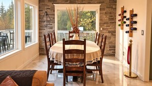 A dining area with a stone wall, a round table, and chairs. - Private Bedroom w Hot Tub and Arcade (Snohomish)