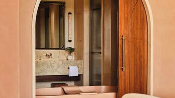 Un baño con lavamanos de mármol, un espejo, una toalla y una puerta de madera.