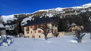 Un edificio de varios pisos con techo inclinado, rodeado de nieve y montañas.