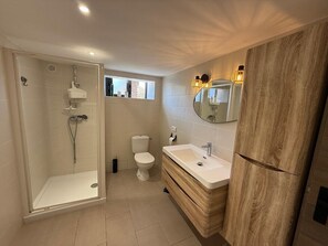 Une salle de bain moderne avec une douche à parois de verre, des toilettes et un meuble-lavabo avec un miroir.