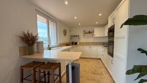 Una cocina moderna con armarios blancos, una barra de madera y un amplio ventanal.