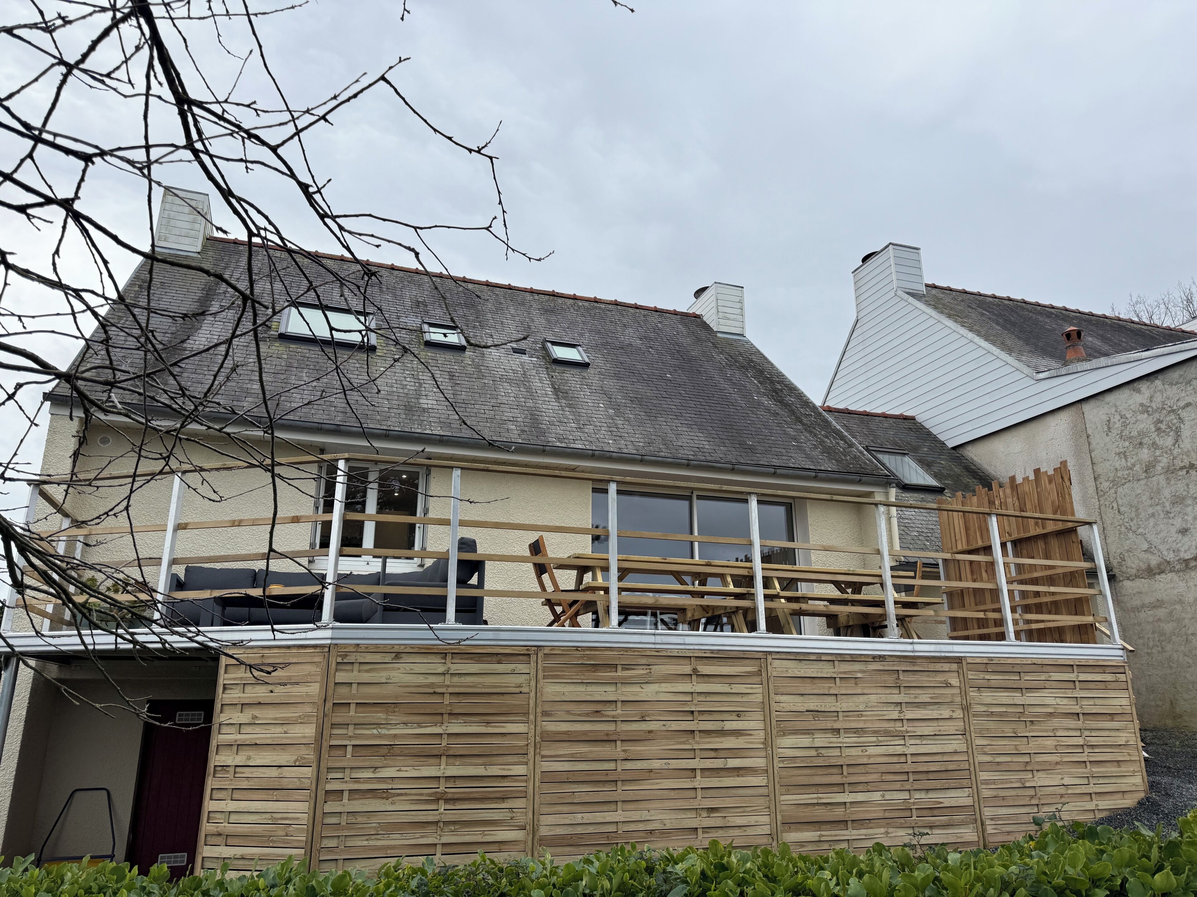 A house with a balcony, a chimney, and a wooden fence.