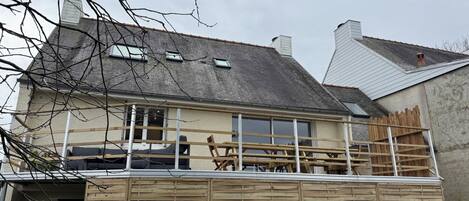 A house with a balcony, a chimney, and a wooden fence.
