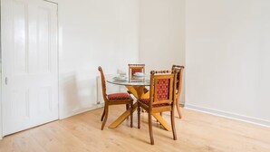 A dining area with a round glass table, four wooden chairs with red cushioned seats, and a white door. - Main Door Private Entrance Apartment (Edinburgh)