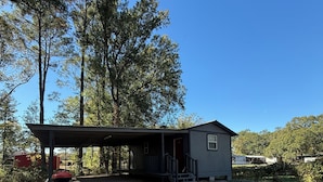 En liten, envåningsbyggnad med en överbyggd veranda och en grill.