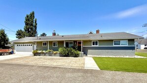 Ein zweistöckiges Haus mit Garage, Veranda und gepflegtem Rasen.