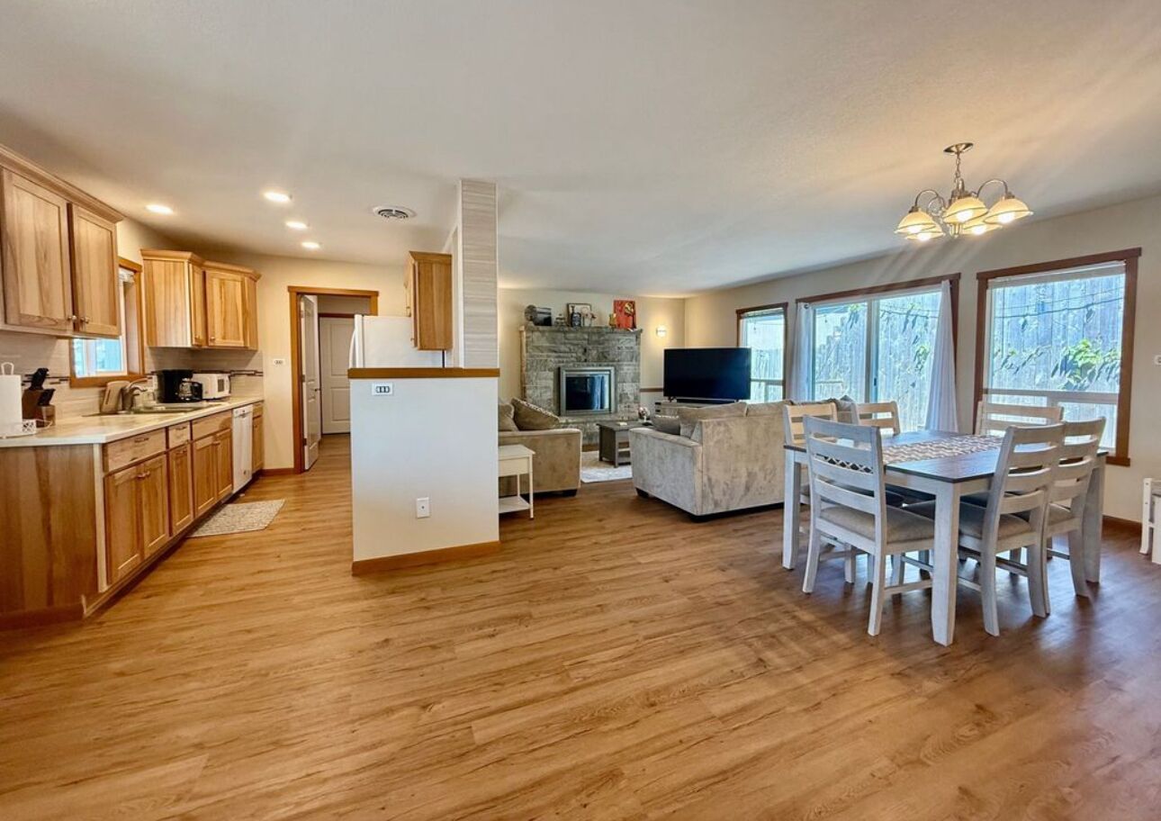 A spacious living area with a dining table and chairs, a fireplace, and a television.