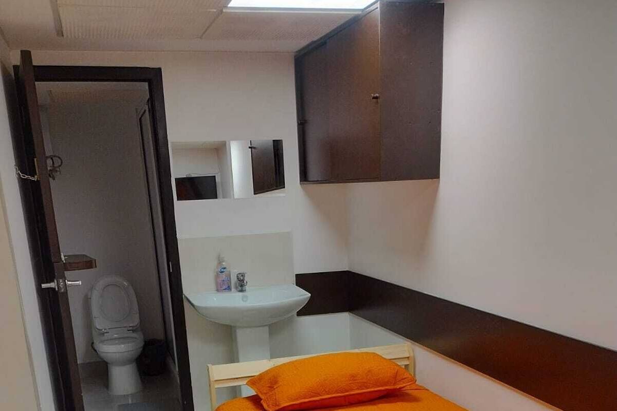 A small room with a bed, a sink, and a toilet.