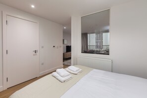 A hotel room with a large bed, a window with a view of the outside, a door, and a mirror on the wall. - Terrace House in Bristol (Bristol)