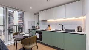 A modern kitchen with a dining area, featuring a built-in oven, microwave, and sink. - Terrace House in Bristol (Bristol)