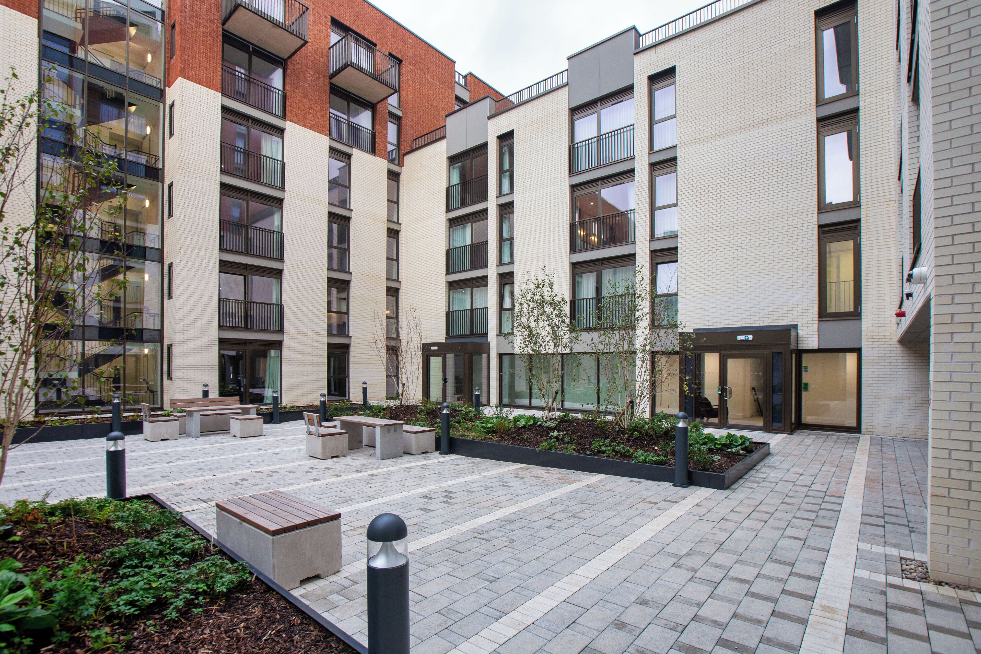A modern building with multiple floors, outdoor seating areas, and a landscaped courtyard.