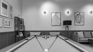 Ein Billardtisch mit Kugeln, eine Couch und gerahmte Kunstwerke an der Wand.
