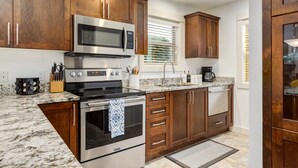A modern kitchen with wooden cabinets, stainless steel appliances, and a granite countertop. - Beach Daze! Peaceful Retreat Near Rathtrevor Beaches (Parksville)