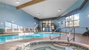 An indoor swimming pool with a tiled floor, a curved hot tub area, and a wooden ceiling. - Beach Daze! Peaceful Retreat Near Rathtrevor Beaches (Parksville)