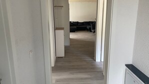 Un corridoio che conduce a un soggiorno con un divano e un frigorifero.