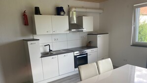 Una cucina moderna con mobili bianchi, piano cottura in acciaio inossidabile e una finestra che illumina naturalmente l'ambiente.