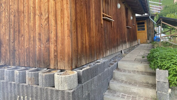 Un edificio in legno con una porta in legno e una scalinata in pietra che conduce a un ingresso coperto.
