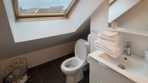 Ein modernes Badezimmer mit Oberlicht, Toilette, Waschbecken und Spiegel.