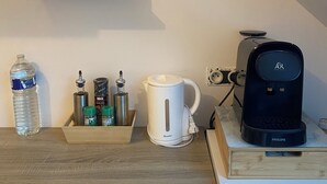 Eine Küche mit Kaffeemaschine, Wasserkocher und Vorratsgläsern auf Regalen.