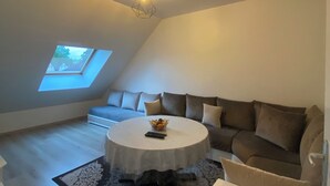 Ein modernes Schlafzimmer im Loft-Stil mit Dachfenster, einem runden Esstisch, einer Couch und einem gemusterten Teppich.