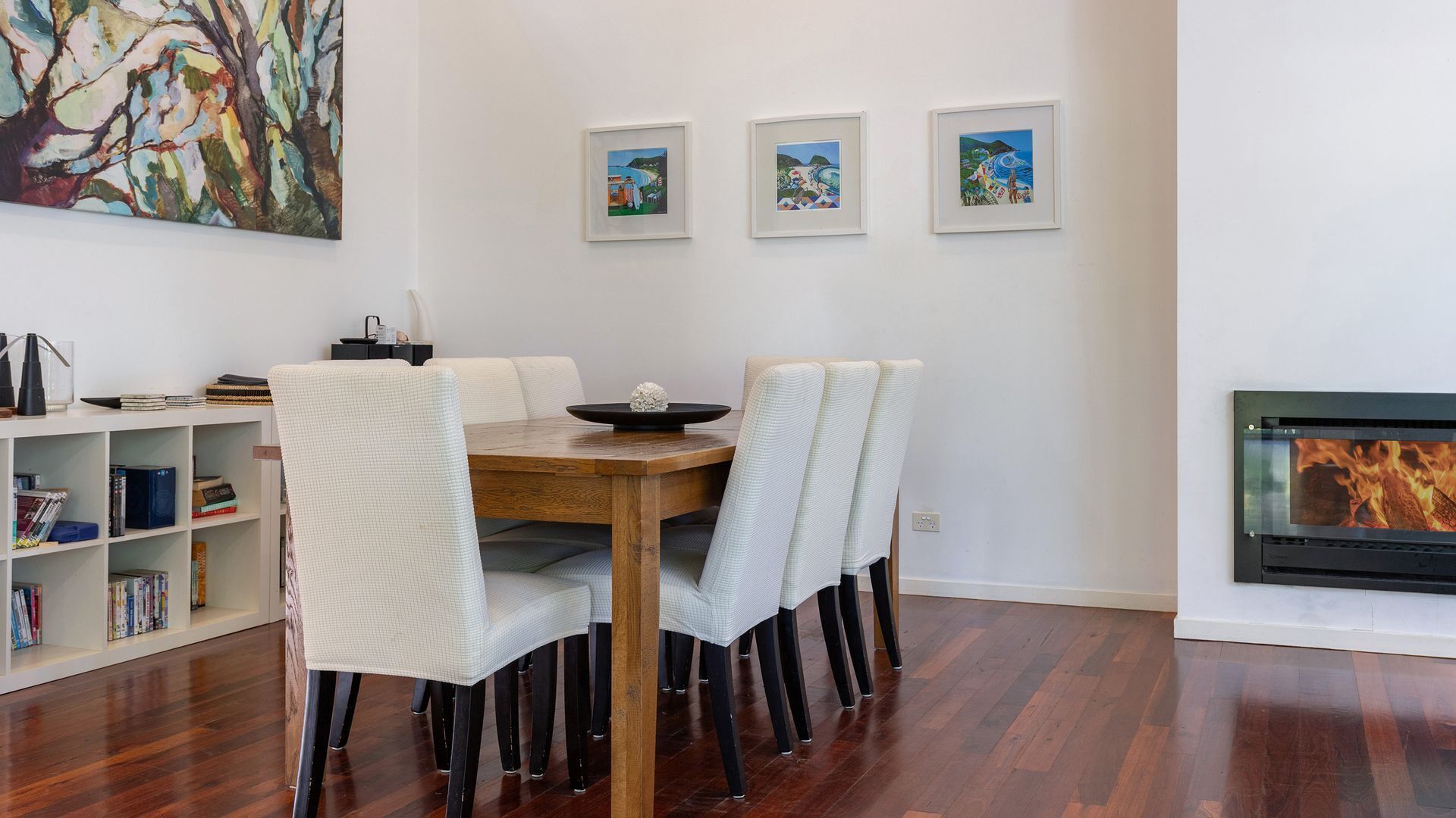 Un comedor con mesa y sillas de madera, una estantería y una chimenea.