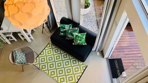 A modern living area with a black sofa, green patterned pillows, a patterned rug, and a large orange pendant light. - No1 Stylish Beach House With Pool (Florianópolis)