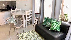 A modern living room with a black sofa, patterned rug, and green leaf-patterned pillows. - No1 Stylish Beach House With Pool (Florianópolis)