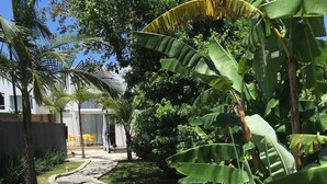 A curved stone pathway leading to a building with a white exterior and a covered outdoor seating area. - No1 Stylish Beach House With Pool (Florianópolis)