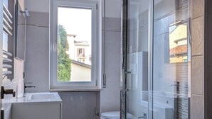 Un baño moderno con ducha acristalada, inodoro y lavamanos.