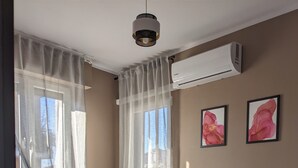 Un dormitorio con una cama, aire acondicionado y dos cuadros en la pared.