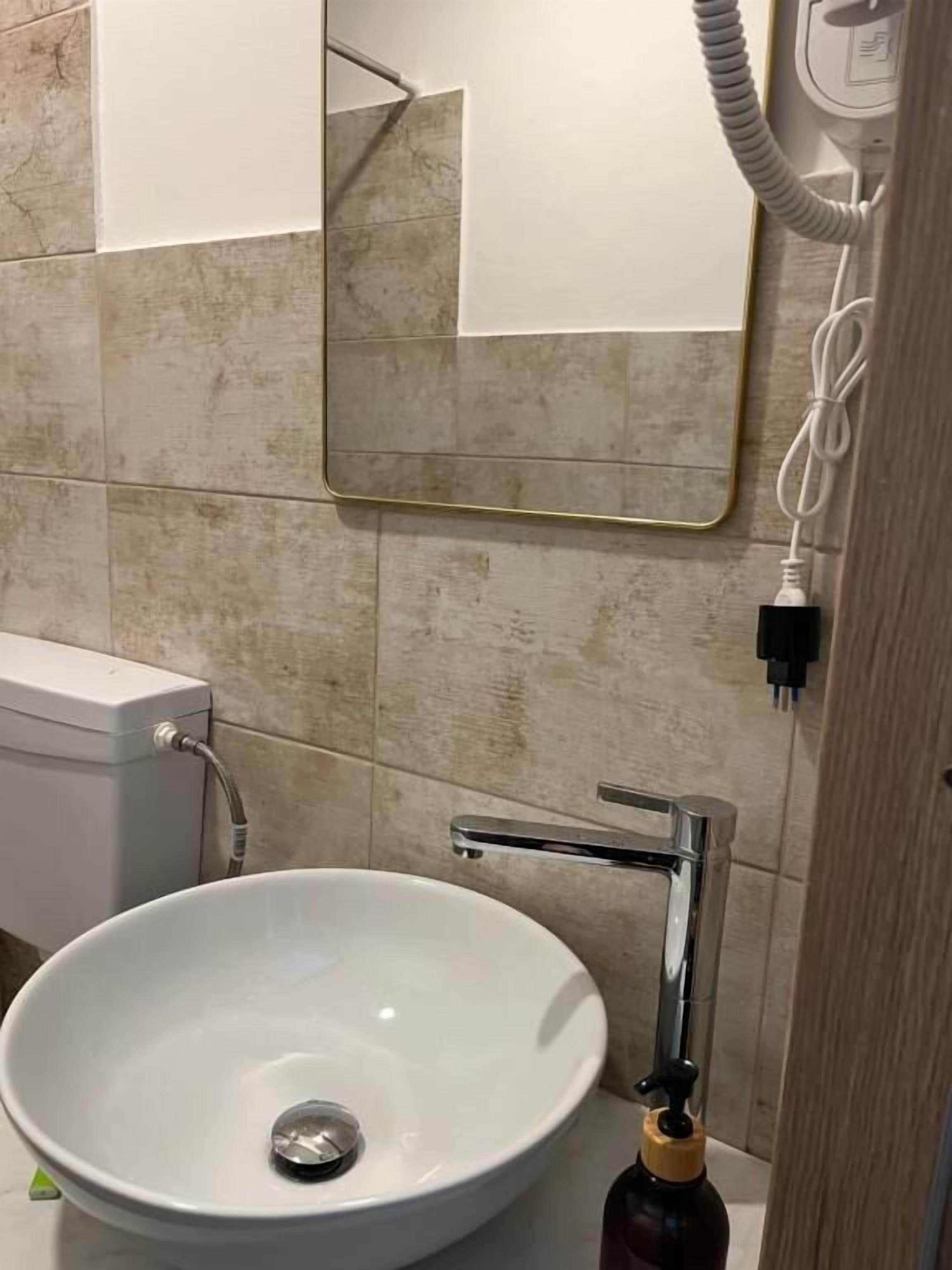 Ein Badezimmer mit einem weißen Waschbecken, einem Spiegel und einer Toilette.