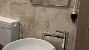 Un baño con un lavamanos blanco, un espejo y un inodoro.