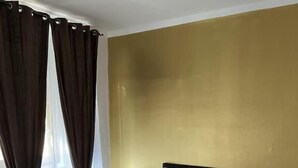 A hotel room with a large bed, wooden headboard, and a gold accent wall. - Genova Gold Rooms (Genoa)