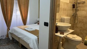 A hotel room with a bed, a bathroom with a sink, toilet, and shower. - Genova Gold Rooms (Genoa)