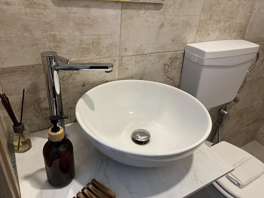 A bathroom with a white sink, a toilet, and a shower area.