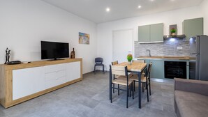 Een moderne keuken met een eethoek, een flatscreen televisie en een inbouwoven.