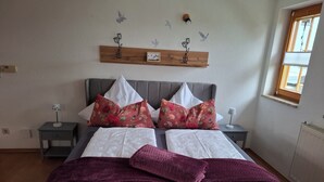 A neatly made bed with floral pillows, a wooden headboard, and a nightstand with a lamp. - Vacation apartment Am Ranis (Oederan)